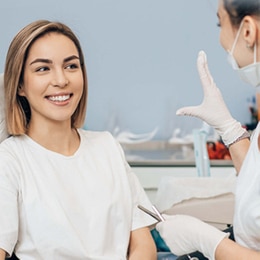 Smiling woman receiving dental examination from dentist in clinical office setting.