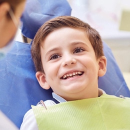 Young boy smiling in dental chair during examination at Gila Ridge Dental office.