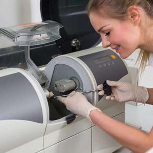 Dental hygienist operates digital imaging equipment during patient examination at dental clinic.