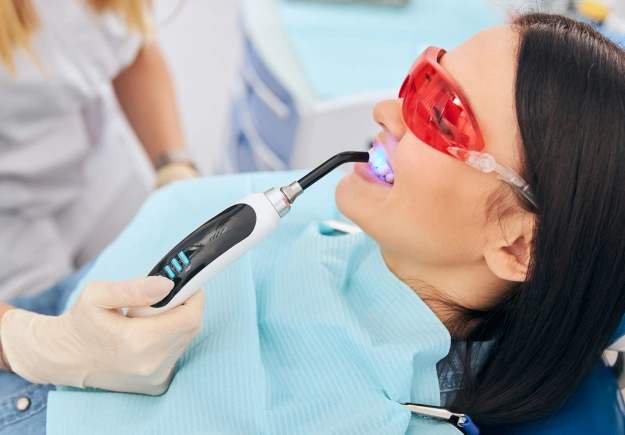 Dental professional performing ultrasonic cleaning procedure on patient's teeth in clinical setting.