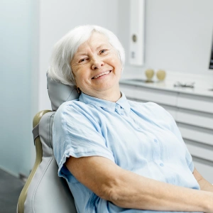 Senior woman smiling in dental chair at modern dental office.